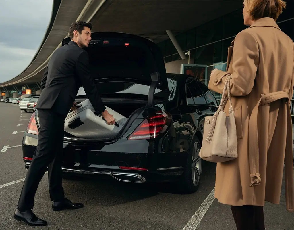 A man loading luggage into luxury car during airport pickup for a client in Ireland.