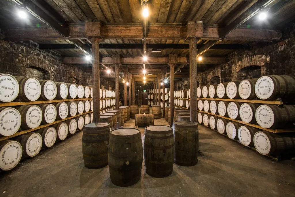 Interior of the Bushmills Distillery warehouse with rows of aging whiskey casks stacked on wooden racks