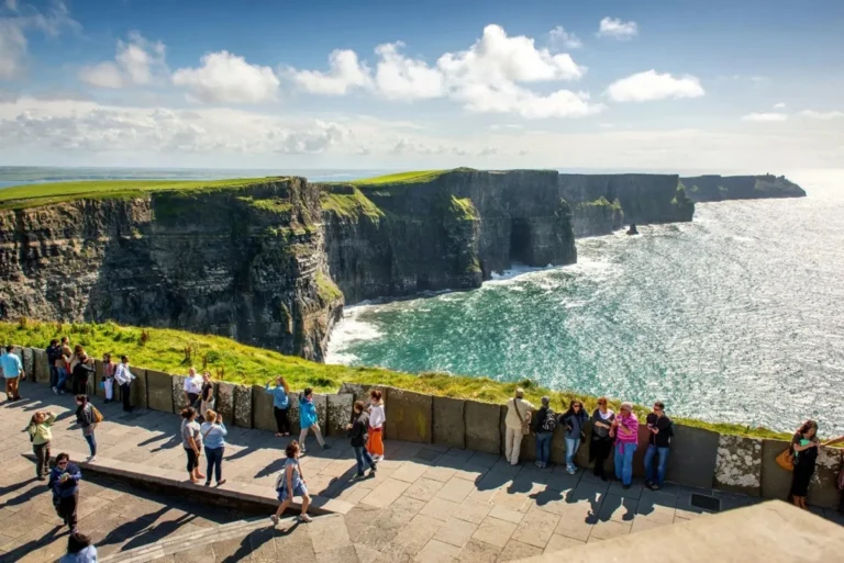 Visitors at the Cliffs of Moher enjoying panoramic views of the Atlantic Ocean on a sunny day in Ireland