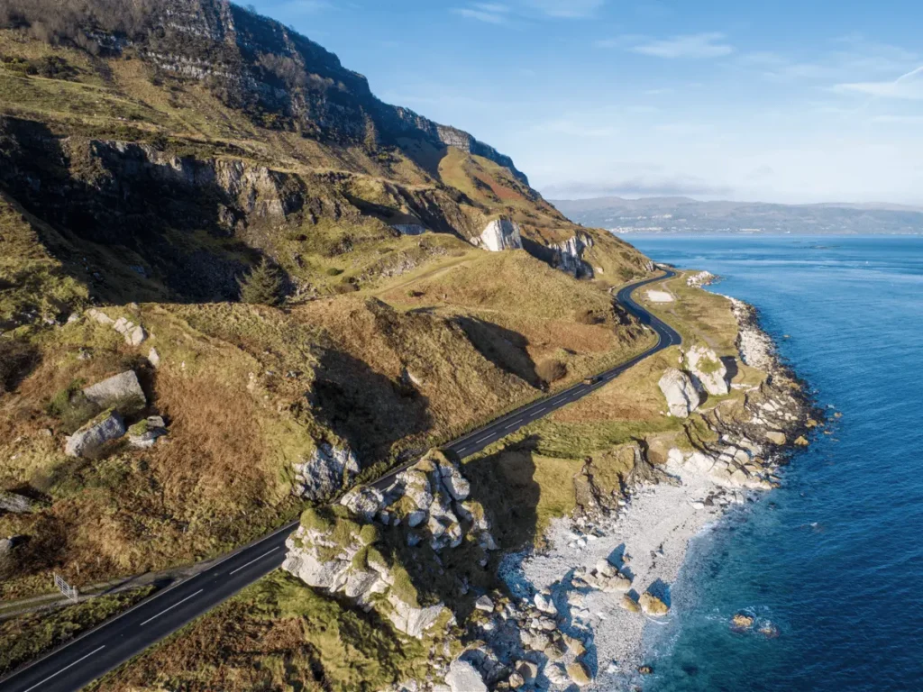 Scenic view of the Mourne Mountains Coastal Drive with winding road, rugged cliffs, and the Irish Sea in the background