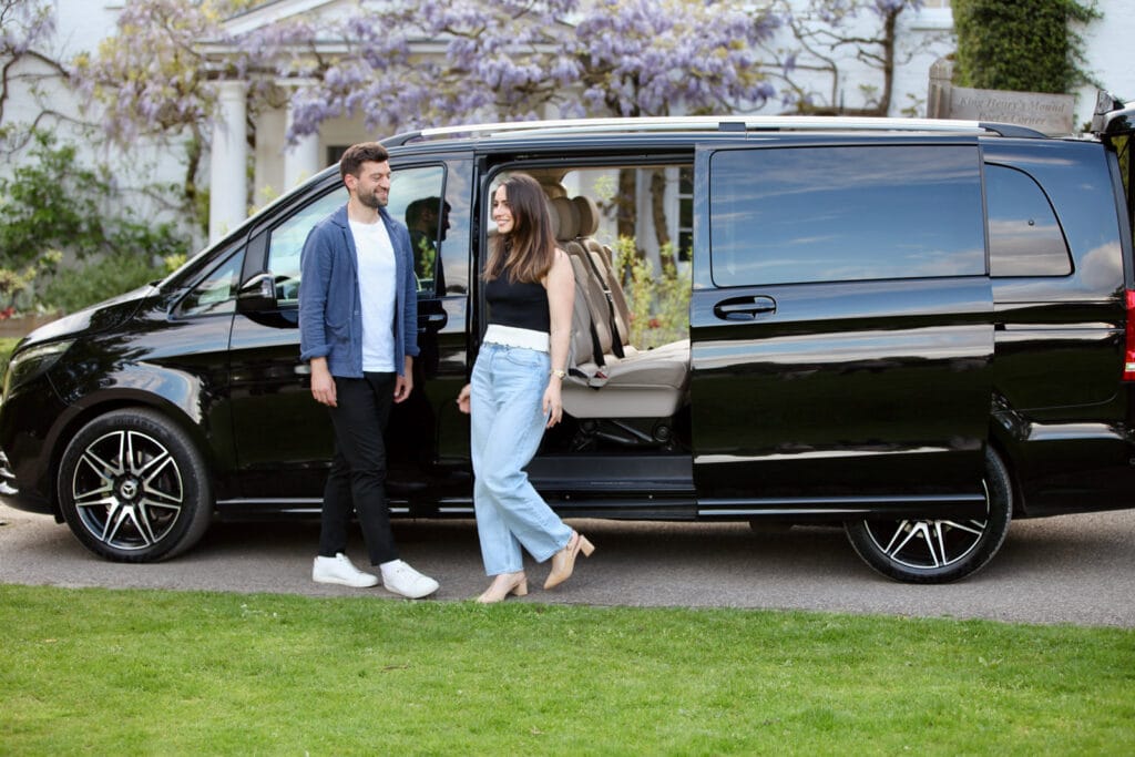 Couple enjoying a private driver tour in Ireland beside a luxury black Mercedes V-Class.