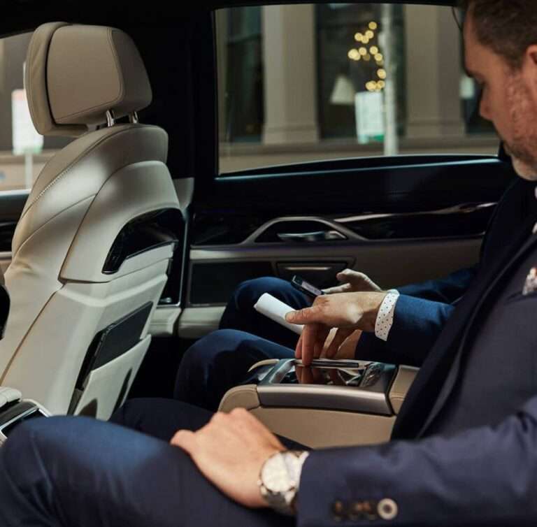 Two business professionals in suits enjoying a comfortable ride with chauffeur services in Dublin.