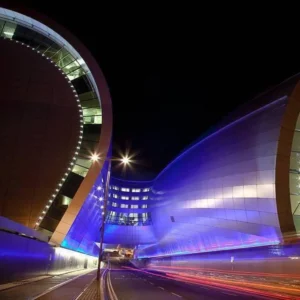 Night view of the road leading to Terminal 1 drop-off at Dublin Airport, featuring modern architecture and light trails.